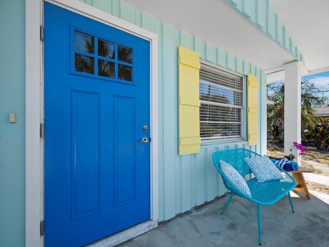 property entrance with covered porch and board and batten siding