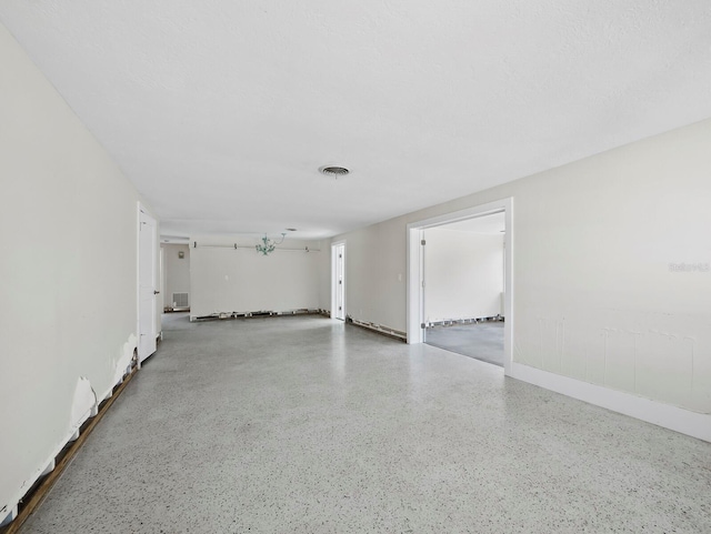 empty room featuring visible vents, a textured ceiling, and speckled floor