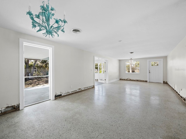 unfurnished living room with speckled floor and visible vents