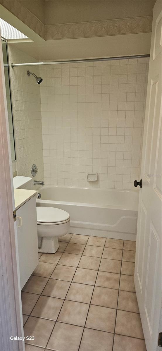 bathroom featuring toilet, shower / bathtub combination, tile patterned flooring, and vanity