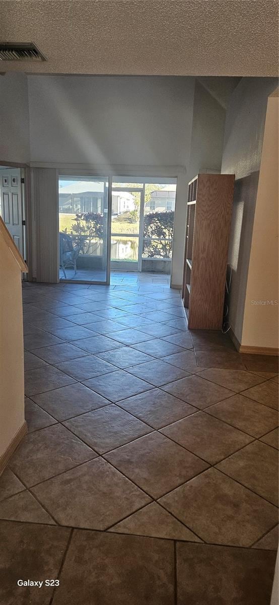 unfurnished room featuring a textured ceiling, visible vents, and baseboards