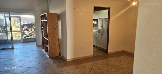 corridor featuring light tile patterned floors and baseboards