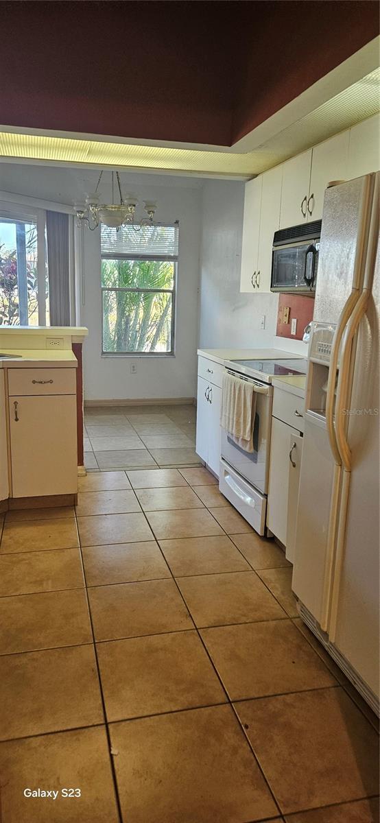 kitchen with white cabinetry, white appliances, light countertops, and light tile patterned floors