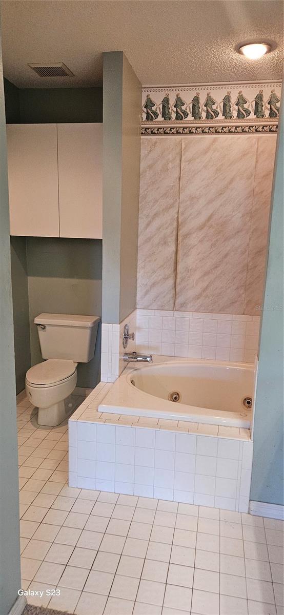 bathroom with toilet, a garden tub, tile patterned flooring, and visible vents