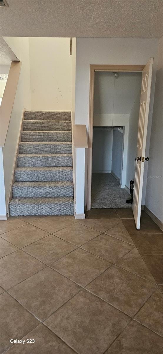 stairs with a textured ceiling and tile patterned flooring