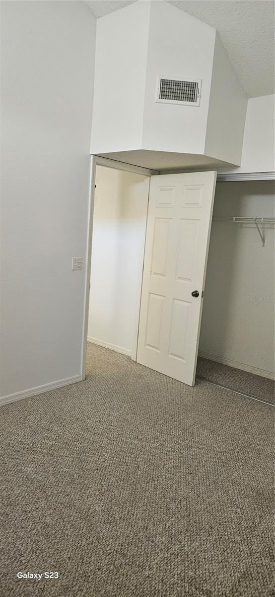 unfurnished bedroom with a closet, visible vents, dark carpet, a textured ceiling, and baseboards