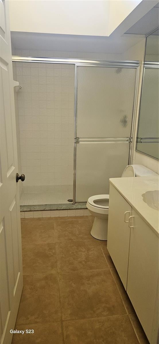 bathroom featuring toilet, tile patterned flooring, tiled shower, and vanity