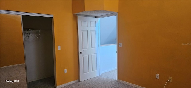 unfurnished bedroom with a closet, light carpet, and baseboards