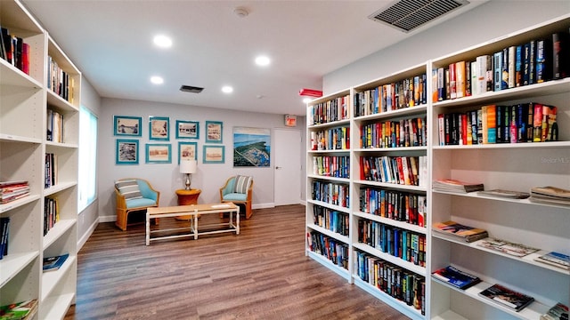 sitting room featuring bookshelves, wood finished floors, and visible vents