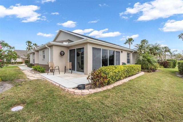 rear view of property featuring a patio area, a lawn, and stucco siding