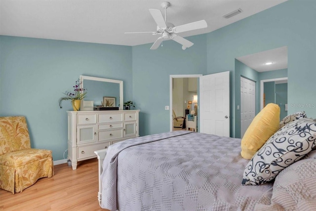 bedroom featuring light wood-type flooring, visible vents, lofted ceiling, a ceiling fan, and baseboards