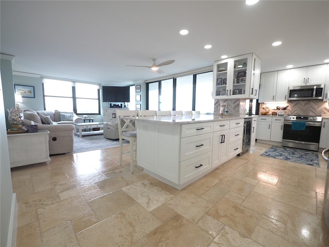 kitchen with wine cooler, stone tile floors, stainless steel appliances, recessed lighting, and open floor plan