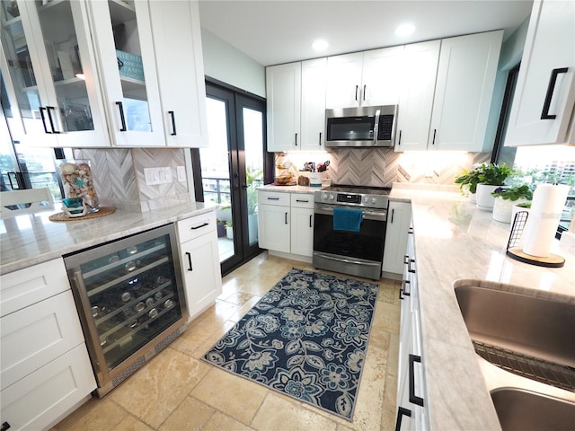 kitchen with light stone counters, wine cooler, backsplash, appliances with stainless steel finishes, and white cabinetry