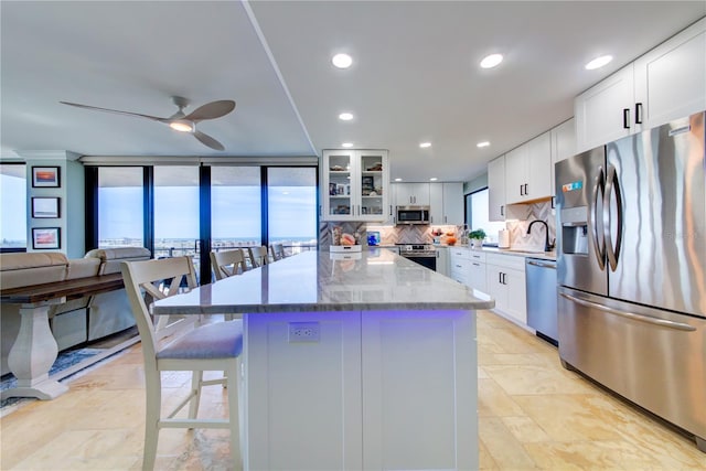 kitchen with tasteful backsplash, glass insert cabinets, a breakfast bar area, light stone countertops, and stainless steel appliances