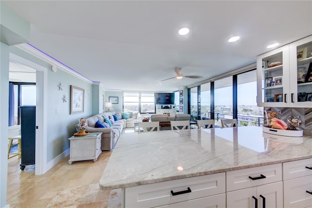 kitchen with a peninsula, glass insert cabinets, light stone countertops, and white cabinets