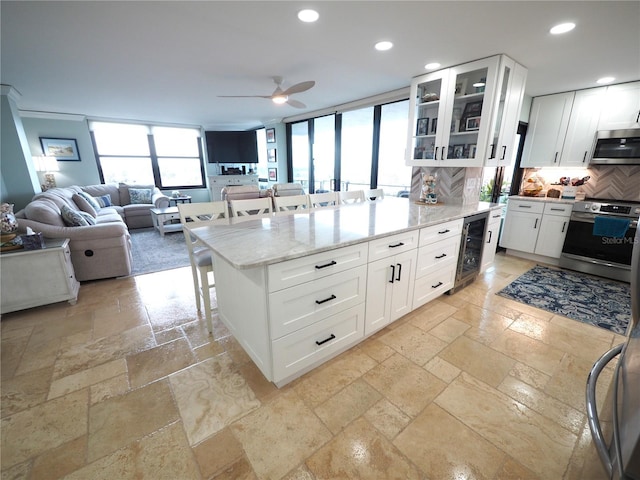 kitchen featuring stone tile floors, a kitchen bar, stainless steel appliances, and recessed lighting