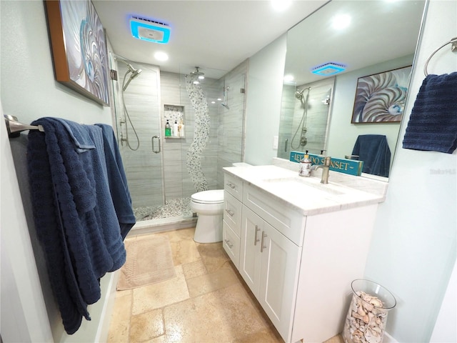 bathroom with stone tile flooring, toilet, a shower stall, and vanity