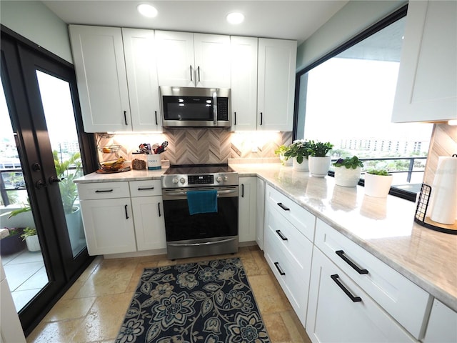 kitchen featuring light stone counters, white cabinetry, appliances with stainless steel finishes, backsplash, and stone tile flooring