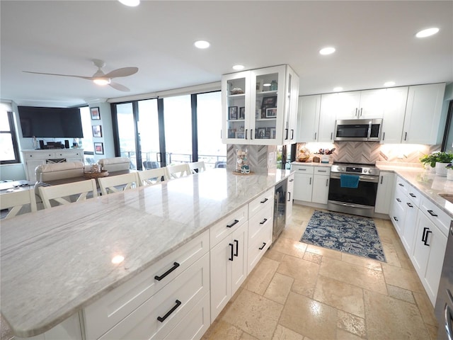 kitchen featuring recessed lighting, stone tile flooring, backsplash, appliances with stainless steel finishes, and beverage cooler