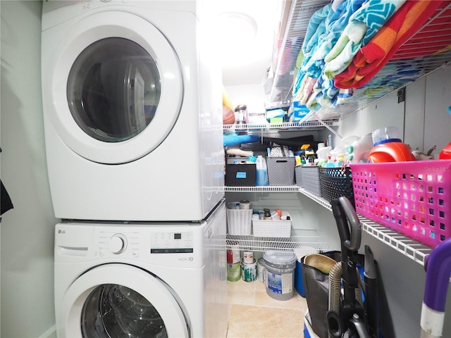 laundry area with laundry area, tile patterned flooring, and stacked washing maching and dryer