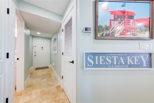 hall featuring stone finish flooring and baseboards