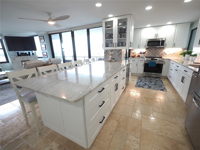 kitchen featuring recessed lighting, stainless steel appliances, a kitchen breakfast bar, backsplash, and stone tile flooring