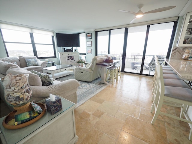 living room featuring a ceiling fan, stone tile flooring, and floor to ceiling windows