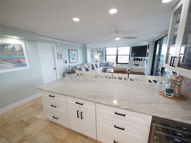 kitchen with recessed lighting, beverage cooler, white cabinets, baseboards, and light stone countertops