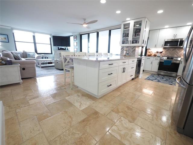 kitchen featuring a breakfast bar, recessed lighting, stone tile flooring, appliances with stainless steel finishes, and open floor plan