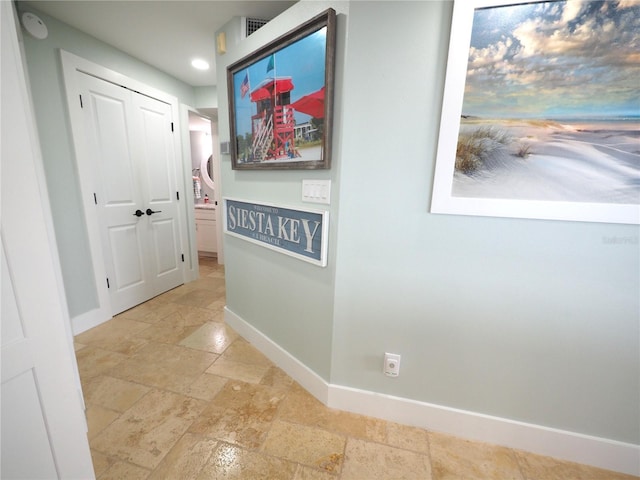 corridor with baseboards and stone tile floors