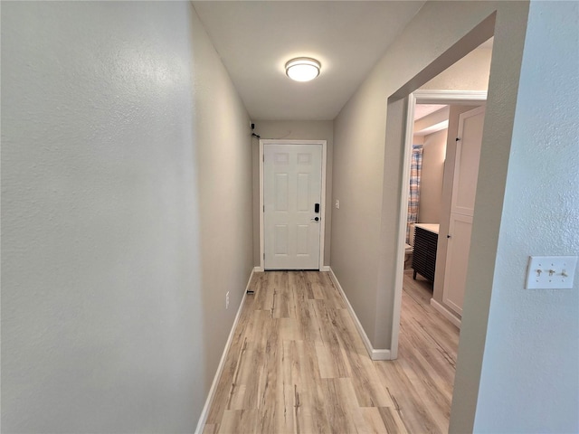 hallway featuring light wood-type flooring and baseboards