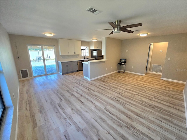 kitchen featuring white cabinets, appliances with stainless steel finishes, open floor plan, a peninsula, and light countertops