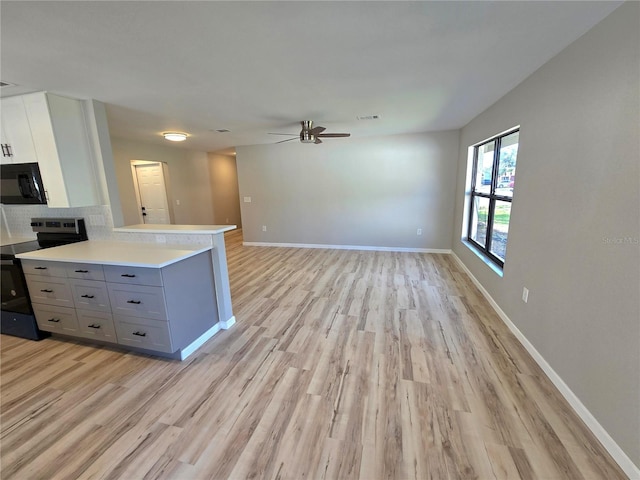 kitchen featuring light countertops, electric range oven, open floor plan, white cabinets, and black microwave