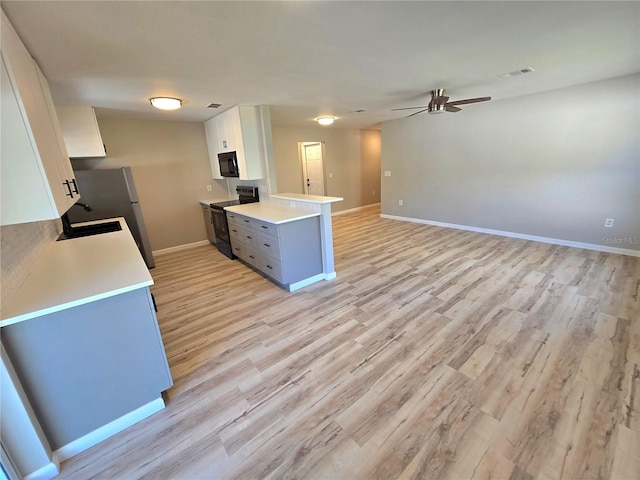 kitchen with electric stove, visible vents, freestanding refrigerator, open floor plan, and white cabinetry