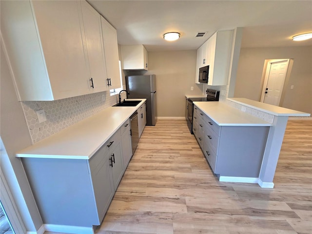 kitchen featuring visible vents, white cabinets, appliances with stainless steel finishes, a peninsula, and light countertops