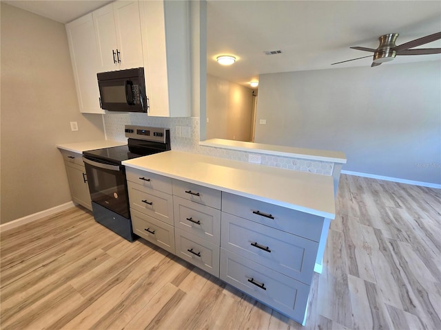 kitchen with tasteful backsplash, a peninsula, light countertops, black appliances, and white cabinetry