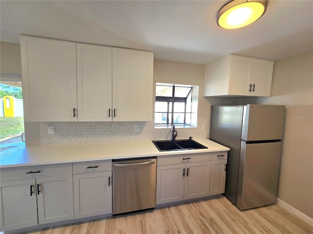 kitchen featuring light wood finished floors, light countertops, appliances with stainless steel finishes, white cabinets, and a sink