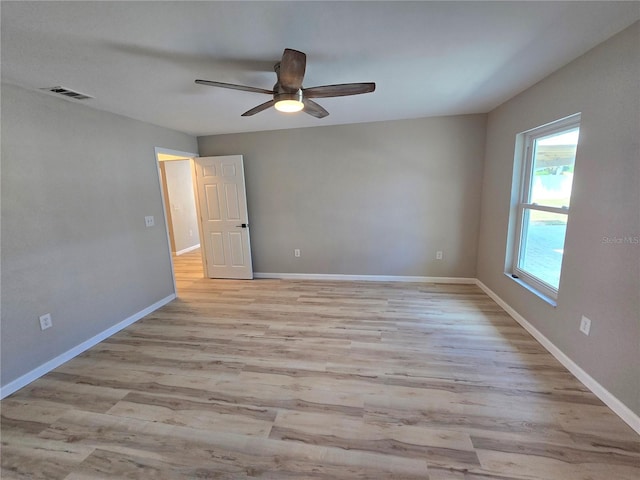 empty room with light wood finished floors, baseboards, visible vents, and a ceiling fan