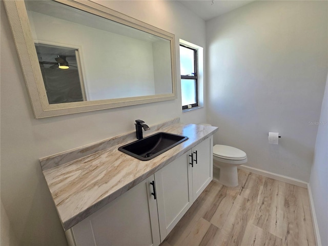 bathroom with baseboards, vanity, toilet, and wood finished floors