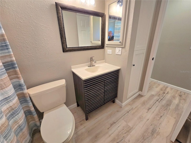 full bathroom featuring toilet, baseboards, wood finished floors, and vanity