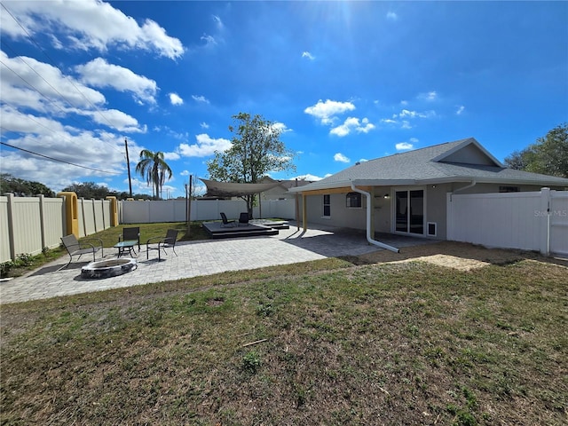 rear view of house with a fire pit, a lawn, a patio area, and a fenced backyard