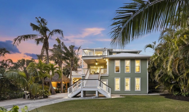 rear view of house featuring stairway, a lawn, a balcony, and a ceiling fan