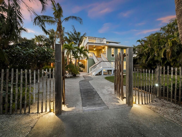 view of front of property with a fenced front yard, a gate, stairway, and a ceiling fan