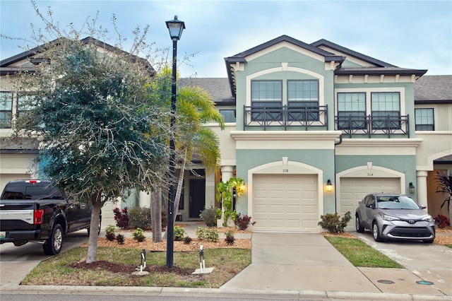 view of property with concrete driveway, a shingled roof, a balcony, and stucco siding