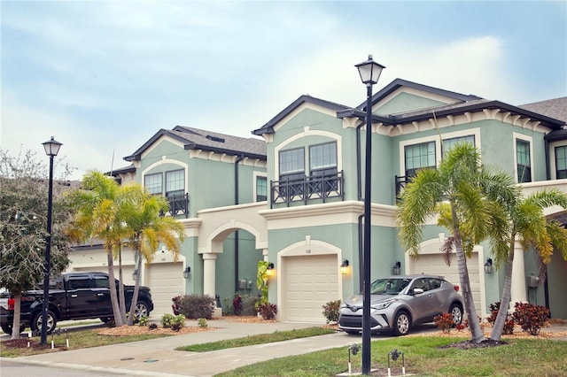 view of front of property with a garage, concrete driveway, a balcony, and stucco siding