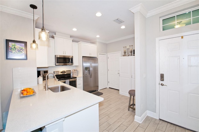 kitchen with crown molding, appliances with stainless steel finishes, light countertops, and a sink