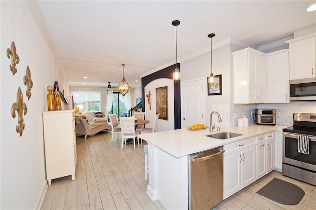 5118 78th St Cir E, Bradenton, FL 34203 - kitchen featuring arched walkways, decorative backsplash, appliances with stainless steel finishes, a peninsula, and a sink