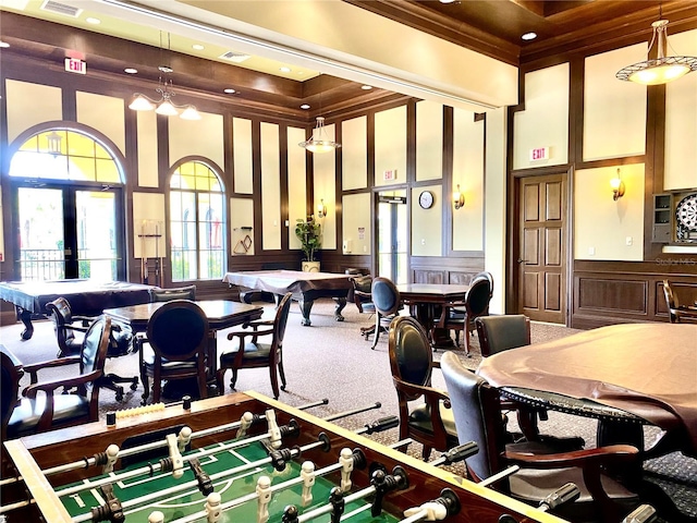 carpeted dining space with a decorative wall, a wainscoted wall, a towering ceiling, french doors, and crown molding