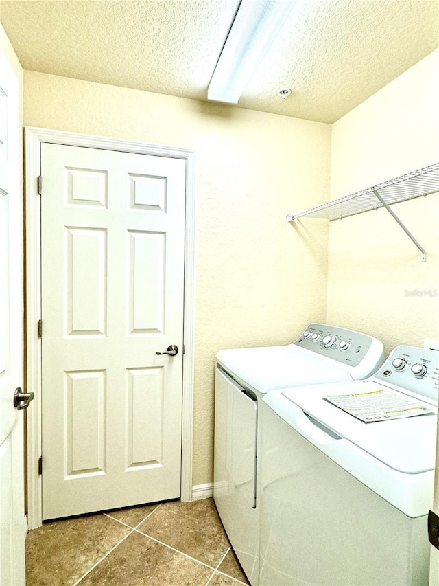 laundry room with washer and clothes dryer, a textured ceiling, tile patterned flooring, laundry area, and baseboards