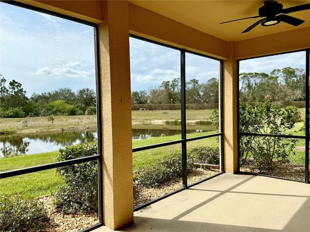 unfurnished sunroom featuring a water view and ceiling fan